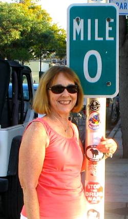 Joyce Hendrix posing with the MILE 0 marker for US-1 on Whitehead Street in Key West